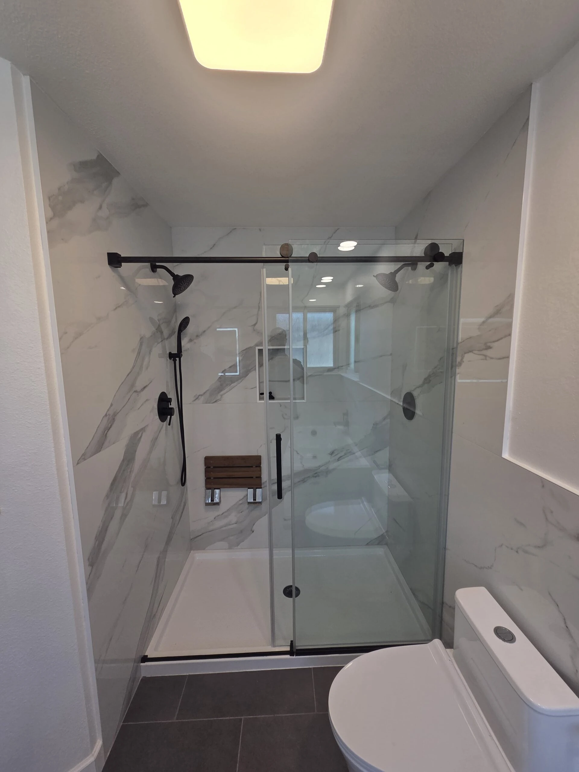 Covington master bathroom shower after remodeling, with light large-format tile and glass enclosure